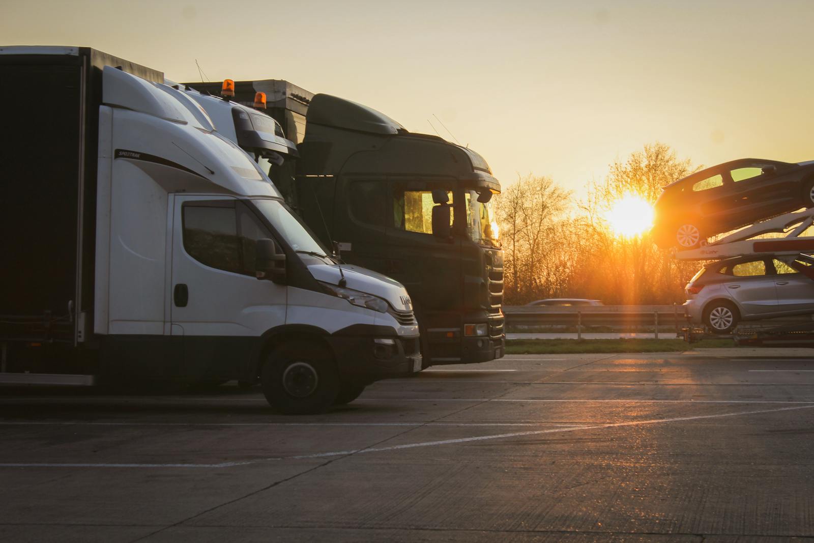Car-hauler trucks at sunset, one loaded with vehicles
